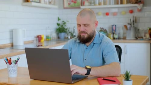 Bearded Man Working on Laptop in Kitchen