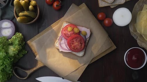 Flat Lay of Chef's Hand Adds Sliced Tomato To the Sandwich with Ham and Vegetables on the Wooden