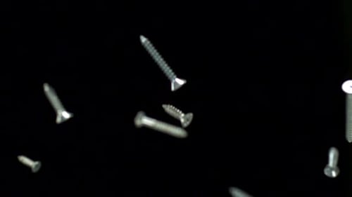 Screws Falling in Slow Motion Against Black