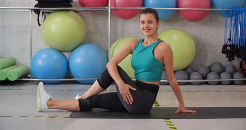 Sport Woman Stretching Legs Sitting on Fitness Carpet in Gym Club. Fitness Woman Practising