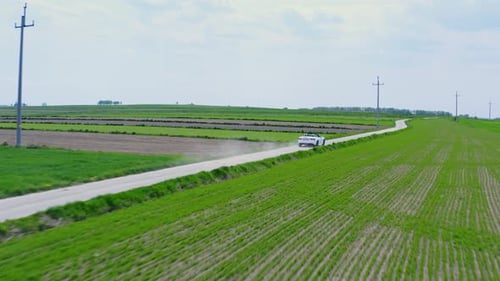 Car Drives Through Rural Green Fields