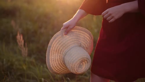 Woman Throws Hat in Sunny Field at Sunset