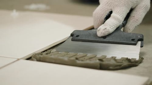 Hand Spreads Mortar with Notched Trowel for Tiling