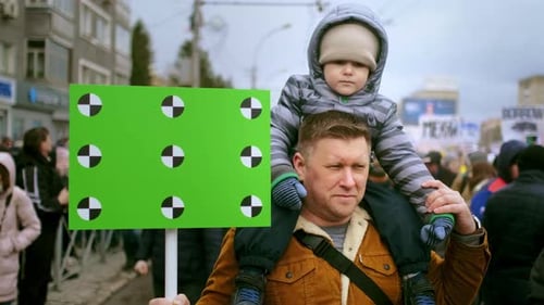 Father Carries Child With Sign at Public Event