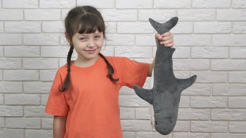 Happy Child Holds a Stuffed Shark Toy