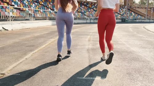 Two Pretty Sportswomen Running on Stadium on Sunset