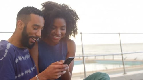Couple using mobile phone in the beach 4k