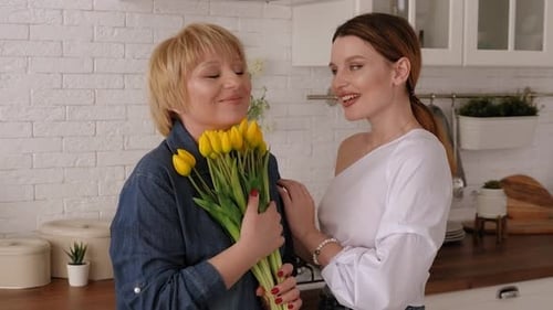 Daughter Gives Mother Yellow Tulips in Kitchen