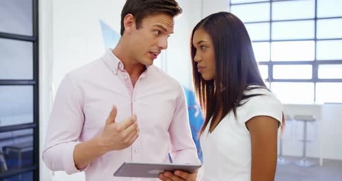 Man and Woman Discussing Data on Tablet in Office