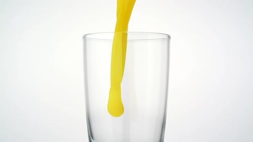 Yellow Liquid Pouring Into Glass on White