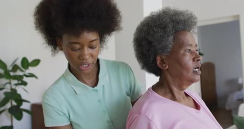 Woman Assists Senior With Arm Exercises at Home