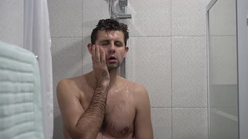 Man Takes a Shower in Tiled Bathroom