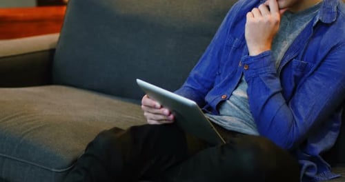 Young Adult on Tablet on Gray Couch