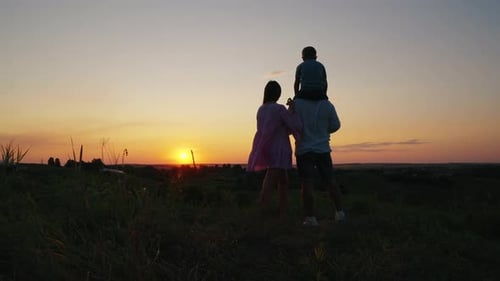 Family Enjoys Scenic Sunset on Grassy Hill