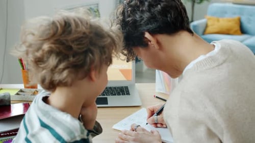Mother and Son Studying Doing Homework Using Laptop with Online School Content at Home