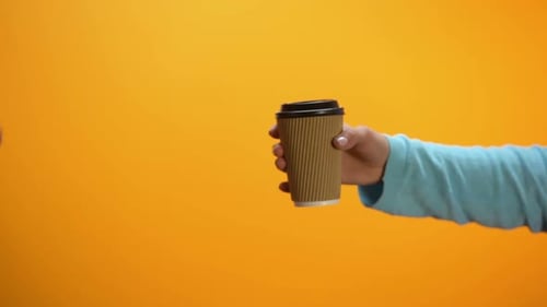 Hand Declines Coffee Cup on Orange Background