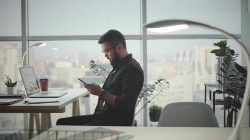 Young Man Typing on Smartphone in Modern Office