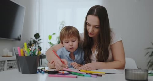 Mother Helping Young Child Drawing at Home