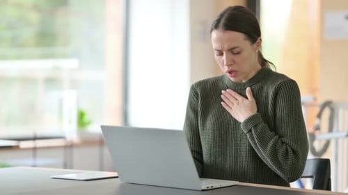 Woman Coughing While Using Laptop in Office