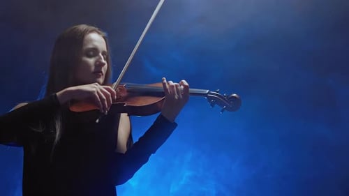 Young Beautiful Woman Playing a Melody on Violin. Smoky Dark Studio