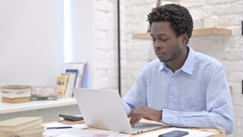 Young Adult Typing on Laptop at Desk