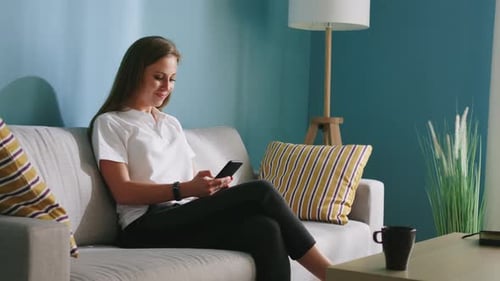 Woman Uses Smartphone on Couch at Home
