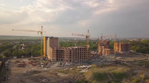 Luftaufnahme einer Baustelle mit Baukränen und Hochhäusern in einer Stadt.
