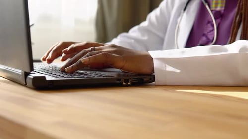 Close Up of Hands of African Woman Doctor Working on Laptop in Clinic