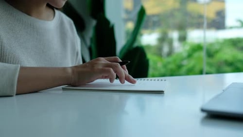 Person Writing in Notebook at Desk Indoors