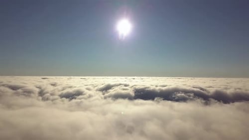 Aerial view from above of white puffy clouds in bright sunny day.
