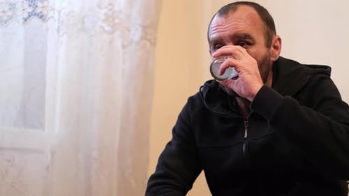 Man Drinks from Glass, Sits Indoors