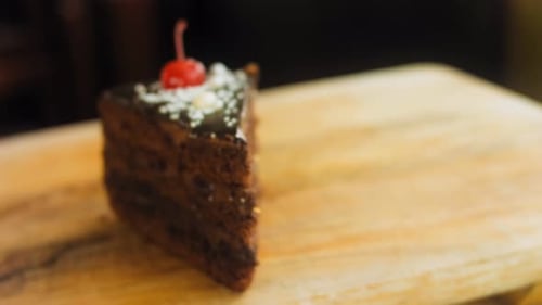 Chocolate Cake Slice Topped with Cherry on Board