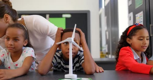 Front view of Caucasian female teacher teaching schoolkids about windmill in the classroom 4k