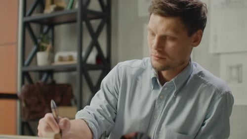 Focused Man Drawing Blueprints at Drafting Table