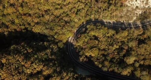 Aerial View of Car Driving Along The Winding Mountain Pass Road Through The Forest Trees. Autumn