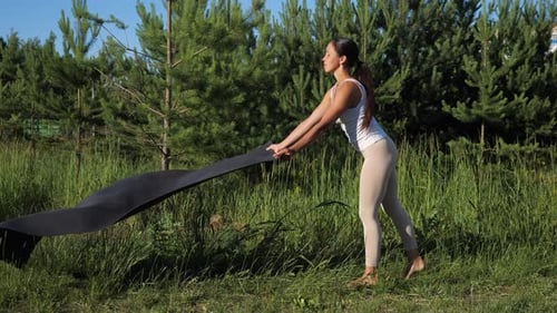 Young Woman Lays Gymnastics Mat on Green Grass