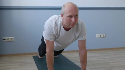 Adult Man Does Plank Pose on Yoga Mat