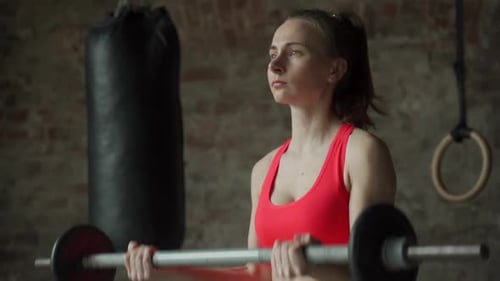 Young Woman Lifts the Barbell Doing Bicep at the Gym