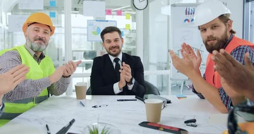 Equipo de constructores y sus jefes masculinos y femeninos que aplauden después de un final exitoso