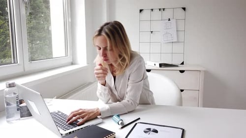 Coughing businesswoman using inhalator in home office