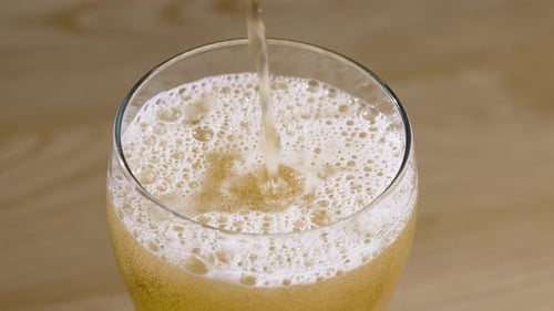 Beer Pouring into Glass Forming White Foam