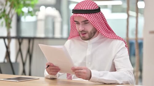 Arab Businessman Celebrating Success on Documents in Office