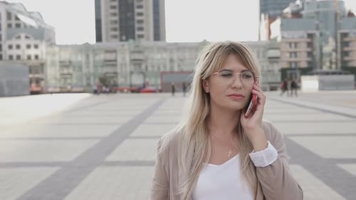 A business girl in a big city is talking on the phone.