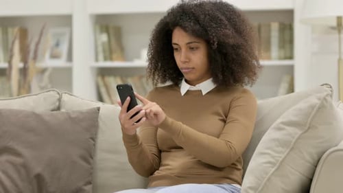Young Woman Using Smartphone on Couch Indoors