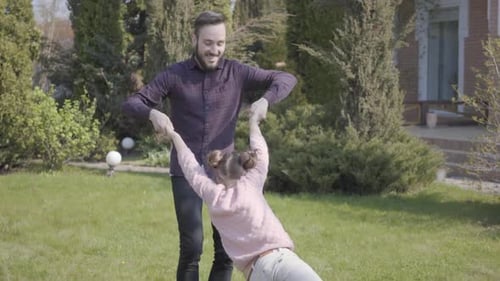 Porträt Junger fröhlicher Vater dreht sich in seinen Armen Seine süße süße Tochter und sie haben Spaß