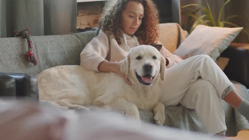 Woman Relaxes with Golden Retriever Dog at Home