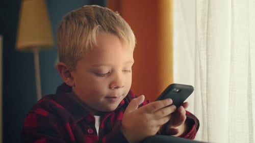 Young Child Using Smartphone Indoors by Window