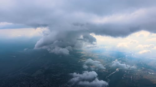 Aerial View From Airplane Window at High Altitude of Distant City Covered with Puffy Cumulus Clouds