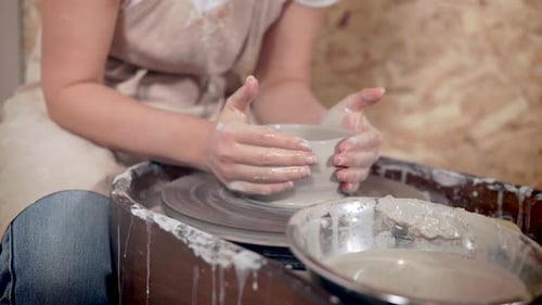 Jeune fille faisant de la poterie sur une roue.