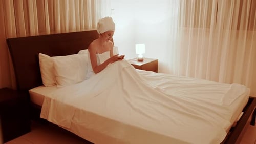 Woman Relaxing in Bed with Mobile Device